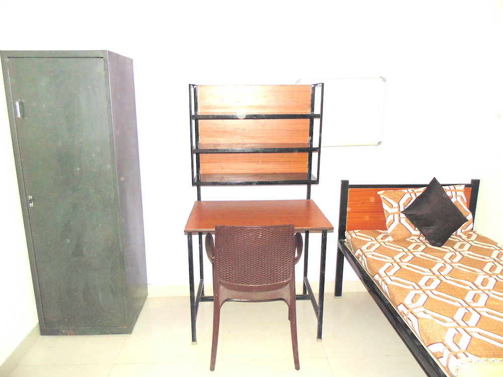 single bed along with brown table, chair and green almirah